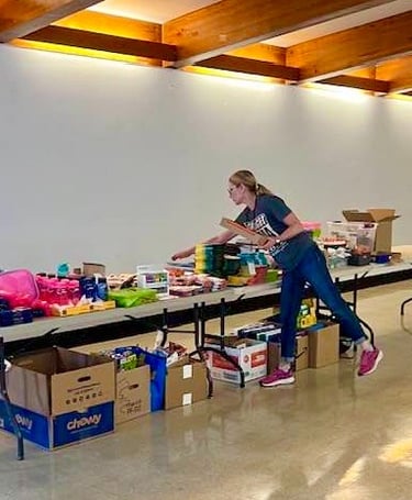 Volunteer woman arranging school supplies on table