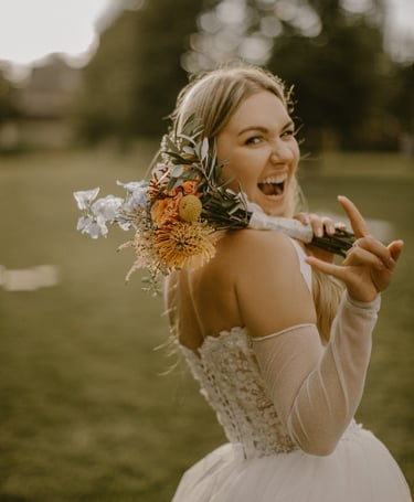 moteris su vestuvine suknele ir margų gėlių puokšte