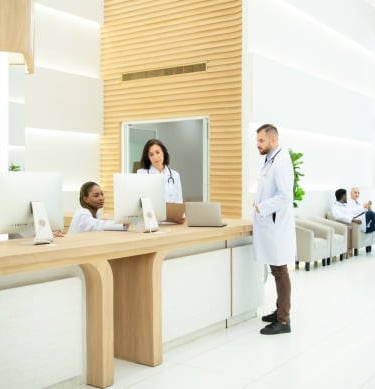 Un médico con bata blanca se encuentra frente al mostrador de recepción de un hospital