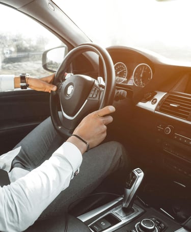 Un hombre sostiene el volante de un coche. Lleva un reloj en la muñeca izquierda