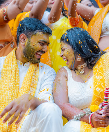 Bride and groom with yellow turmeric, smiling.