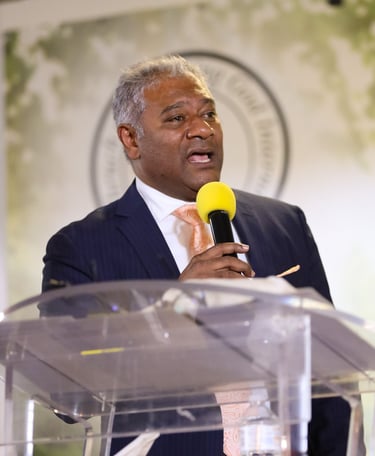Male holding a microphone wearing tie and suit