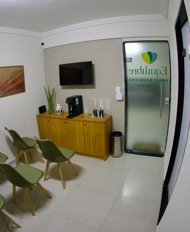 Modern clinic waiting room with green chairs, wooden cabinet, and wall art in a wellness center.