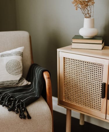 a chair with a blanket on it and a vase with flowers