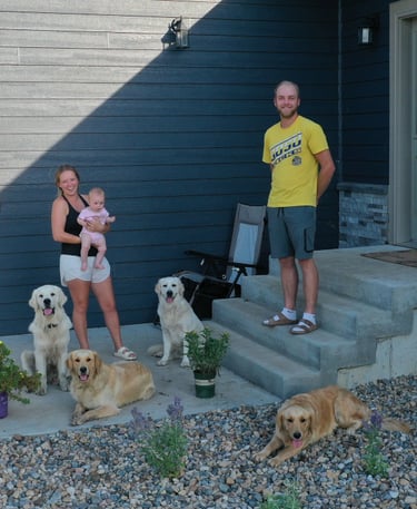 A family with their 4 dogs in front of a house