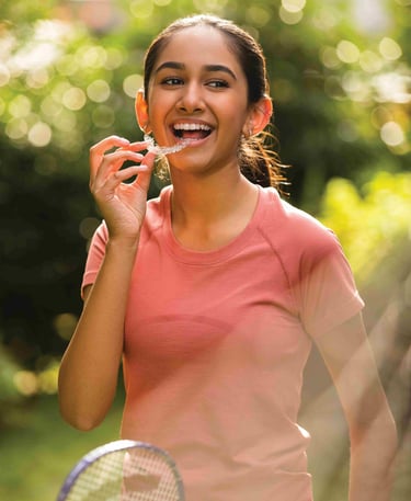 a woman holding a tennis racket and her clear aligners