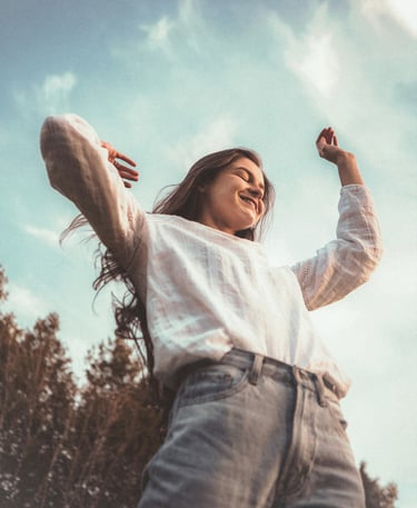 Femme souriante levant les bras au ciel, symbole de transformation réussie