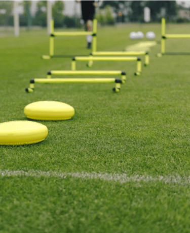 alt="Yellow agility hurdles and cones arranged on a grassy soccer field for Crestline FC"