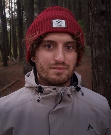 Ritratto di Marco Maggini con berretto rosso e giacca grigia in un bosco