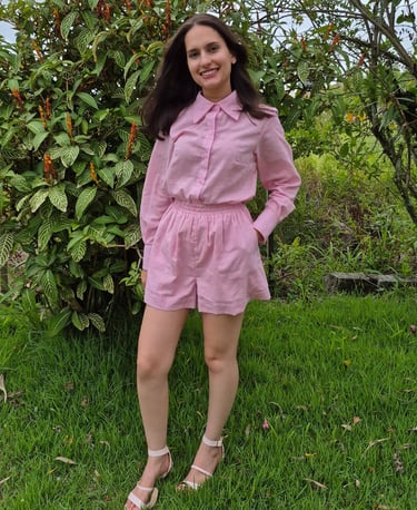 Mulher usando um conjunto rosa claro composto por shorts de elástico e camisa