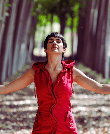 Empowered woman in red dress in the forest, symbolizing financial and spiritual freedom 