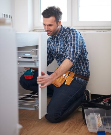 handyman installing kitchen cabinet fittings in an Auckland home