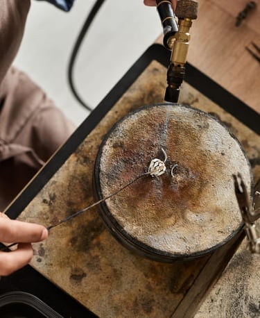 Joyero utilizando un soplete de gas para soldar un anillo de plata sobre un bloque de soldadura 