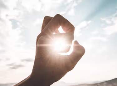 photography of sun glaring through the hole of finger