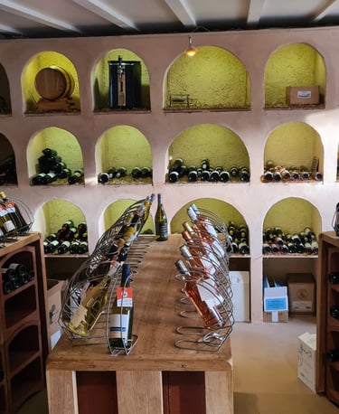 Rustic wine cellar and retail store featuring arched wall shelves and racks filled with assorted wine bottles.