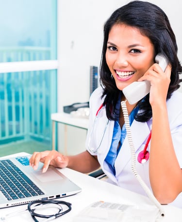 Office staff member talking on the phone to schedule a patient consultation