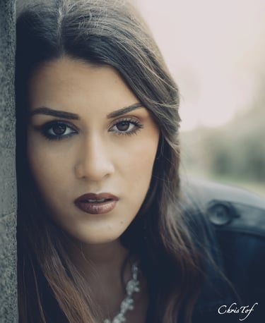 Shooting photo d'une jeune femme aux cheveux bruns longs, appuyée contre un mur.