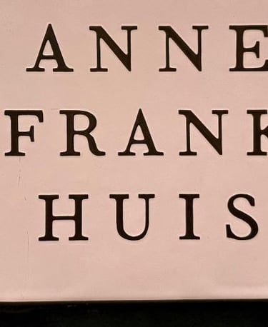 The official Anne Frank Huis museum sign featuring bold black serif typography on a light background.