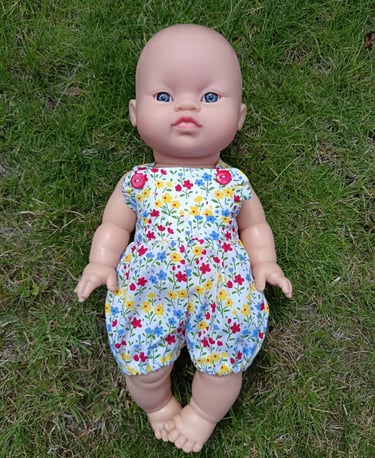 Minikane doll Koko dressed in short floral dungarees