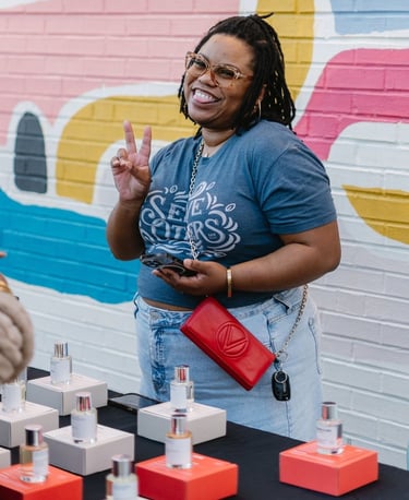 a woman standing in front of a table with a lot of perfumes