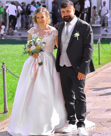 Bride and groom posing together outside a historic cathedral during their wedding ceremony on a sunny day.