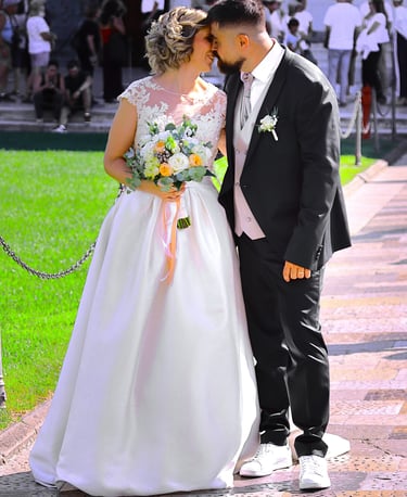Bride and groom posing together outside a historic cathedral during their wedding ceremony on a sunny day.