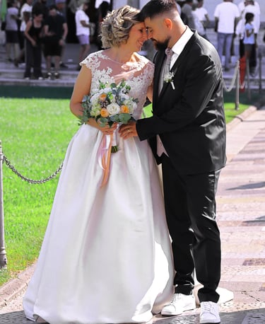 Bride and groom posing together outside a historic cathedral during their wedding ceremony on a sunny day.