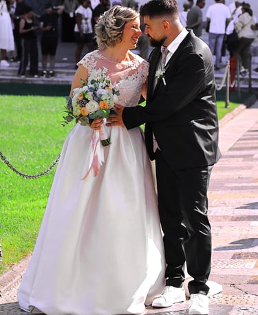 Bride and groom posing together outside a historic cathedral during their wedding ceremony on a sunny day.