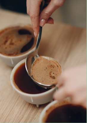 a person is spooning out of a cup of coffee