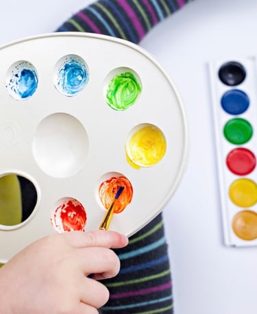 A child holding an art palette mixing colours 
