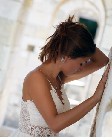 a woman in a white dress standing in front of a stone wall