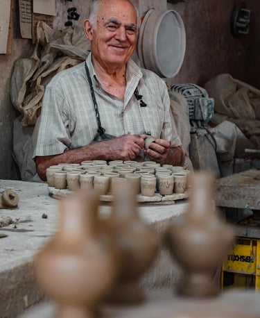 Traditional ceramist in Assemini shaping small handcrafted clay pieces inside his workshop, Sardinia