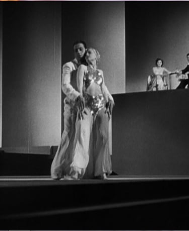 Surreal Busby Berkeley dance tableau of two white‑clad dancers framed by modernist geometric shapes.