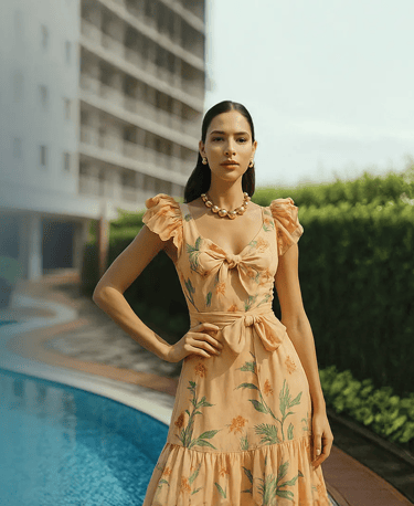 a woman in a dress standing in front of a pool