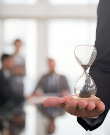 Professional businessman holding a glass hourglass to symbolize corporate time management and deadlines.