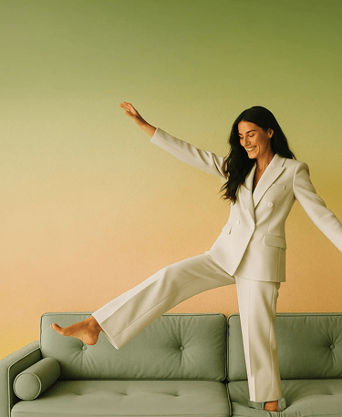 a woman in a white suit and heels is standing on a couch
