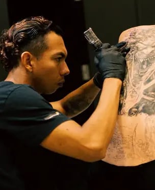 Steven Aguirre, tatuador en Valencia, realizando un tatuaje profesional a un cliente en su estudio