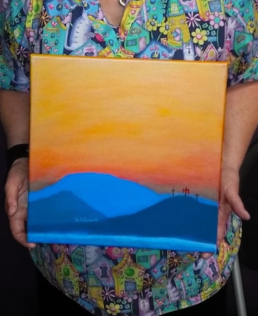 a woman holding a painting of a mountain scene with three crosses
