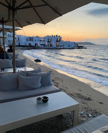a couch with pillows and a coffee table on a beach at sunset