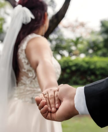 a bride and groom holding hands in a park