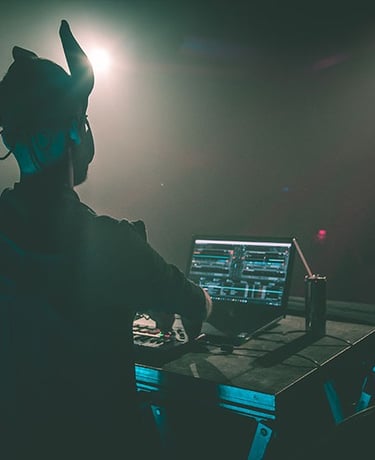 Vue immersive d’un DJ en pleine performance sous des faisceaux colorés, saisie en photo et vidéo par Thomas Bordas.
