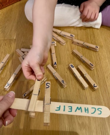 Child matching wooden letter clothespins to a craft stick for a spelling and literacy activity.