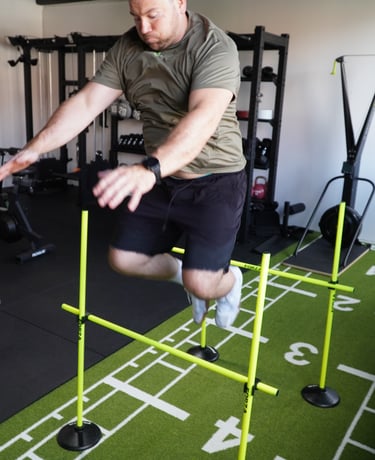 Ein Mann springt über eine Hürde im Fitnessstudio.