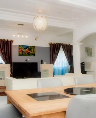 Salon-salle à manger moderne : table en bois, canapés en cuir blanc et arche.