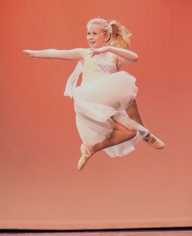 a young girl in a white dress is jumping in the air