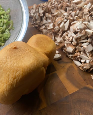 Smoked mozzarella cheese, chopped mushrooms, and sliced celery on a wooden cutting board for cooking preparation.