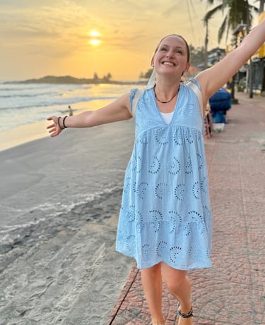 Alena Booth smiling with her hands wide open happy to be in India and seeing the sunset