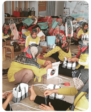 Artisans assembling handmade jali jali woven plastic bags together at Craftvitas Indonesia workshop.