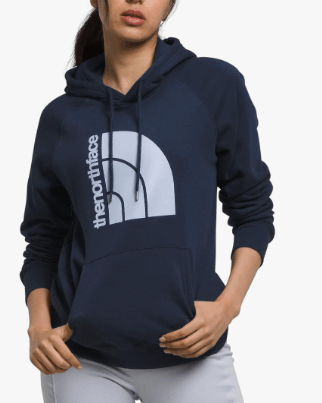 a woman in a blue hoodie and white pants