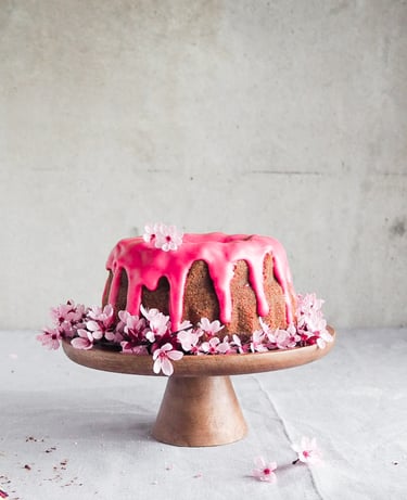 babka oblana różowym lukrem przystrojona kwiatami wiśni